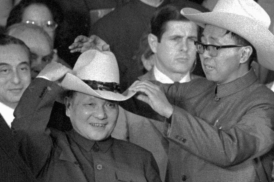 FILE - In this Feb. 2, 1979, file photo, an aide helps Chinese leader Deng Xiaoping try on a cowboy hat presented to him at a rodeo in Simonton, Texas. Four decades after the U.S. established diplomatic ties with communist China, the relationship between the two is at a turning point. (AP Photo, File)