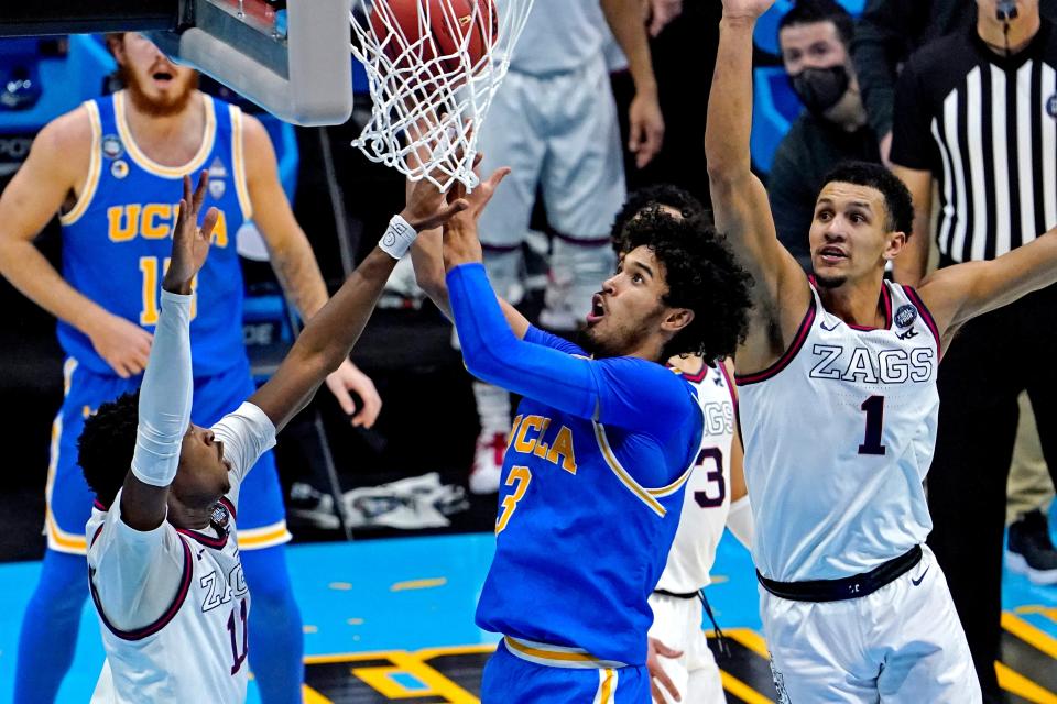 Johnny Juzang (3) shoots against Jalen Suggs (1) and Joel Ayayi (11) during the first half of their Final Four game.