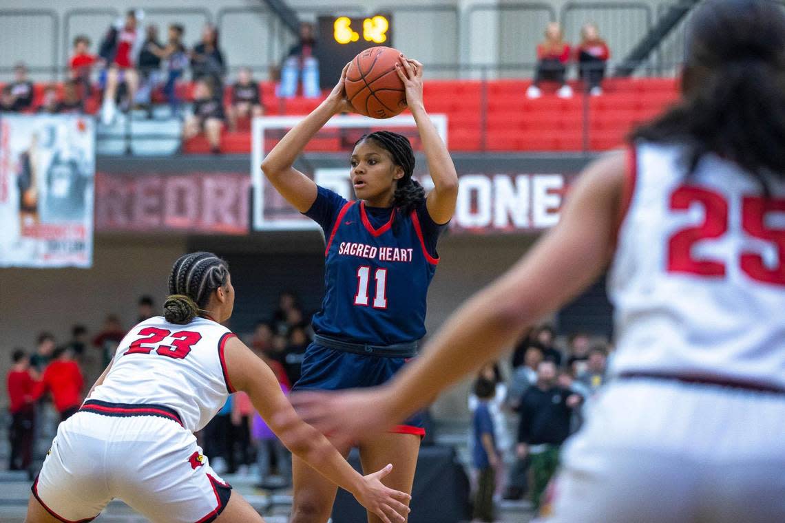 Sacred Heart’s ZaKiyah Johnson (11) looks for an opening while guarded by George Rogers Clark’s Brianna Byars (23) on Feb. 7 in Winchester.