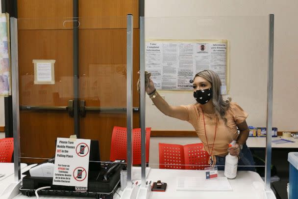 PHOTO: Cameron County early voting clerk Crystal Garcia sanitizes the plastic shields for the poll worker's station, Oct. 15, 2020, before the early voting polling location opens in Brownsville, Texas. (Denise Cathey/The Brownsville Herald via AP)
