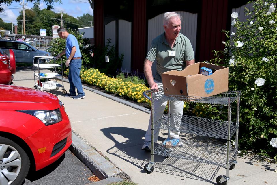 From left, volunteers Joe Guarino and Kevin Joyce assist in curbside delivery at St. Vincent De Paul Community Assistance Center on Monday, Sept. 12, 2022 in Exeter.