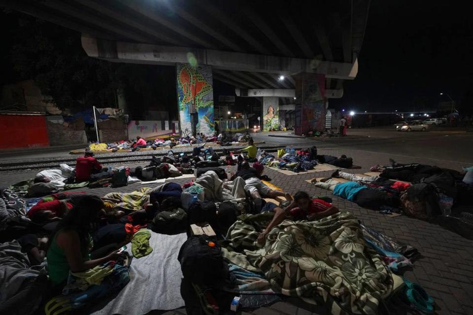 Migrants sleep outside a train station as they wait for the arrival of a northbound freight train, in Irapuato, Mexico, Friday, Sept. 22, 2023.