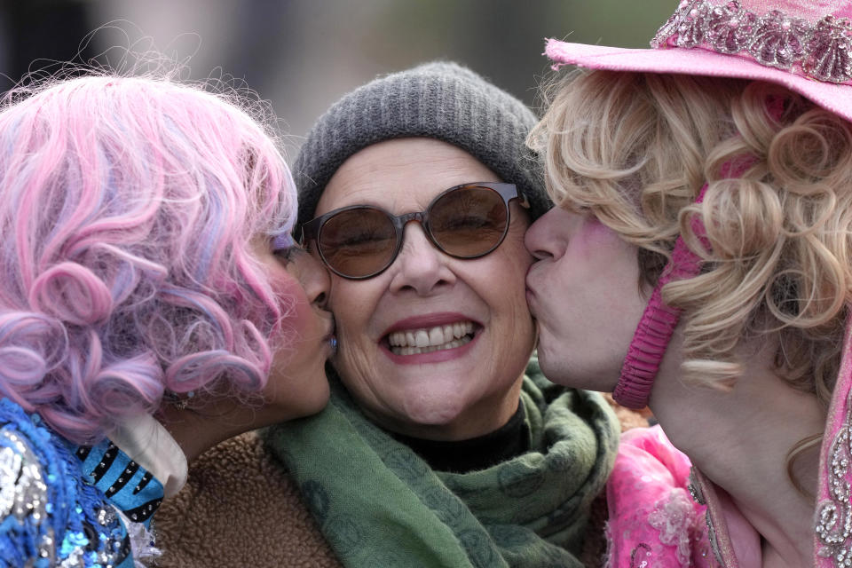 Actor Annette Bening, center, Hasty Pudding 2024 Woman of the Year, receives a kiss from Harvard University theatrical students Nikita Nair, left, and Joshua Hillers, right, while riding in a convertible during a parade, Tuesday, Feb. 6, 2024, through Harvard Yard, in Cambridge, Mass. The award was presented to Bening by Hasty Pudding Theatricals, a theatrical student society at Harvard University. (AP Photo/Steven Senne)