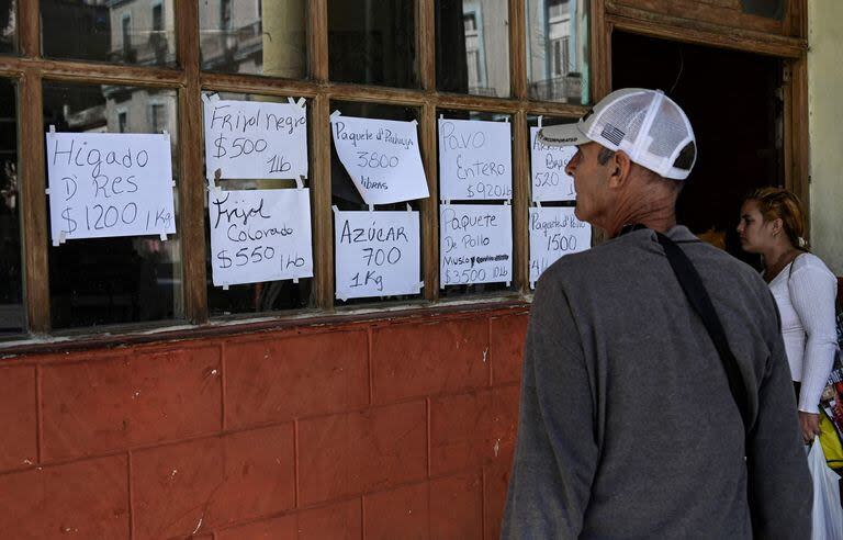 Un grupo de personas miran precios de alimentos en un negocio privado de La Habana (Photo by YAMIL LAGE / AFP)