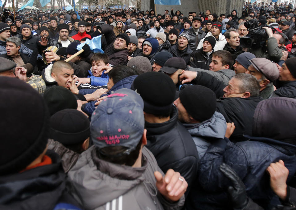 In this photo taken Wednesday, Feb. 26, 2014, pro-Russian protesters, right, clash with Crimean Tatars in front of a local government building in Simferopol, Crimea, Ukraine. The arrival of Russian troops in Crimea has opened old wounds among the Crimean Tatars, who once again fear they will be unwelcome in their homeland. This time, however, some are organizing community watch patrols to protect their families and homes in a place they feel should remain part of Ukraine. (AP Photo/Darko Vojinovic)