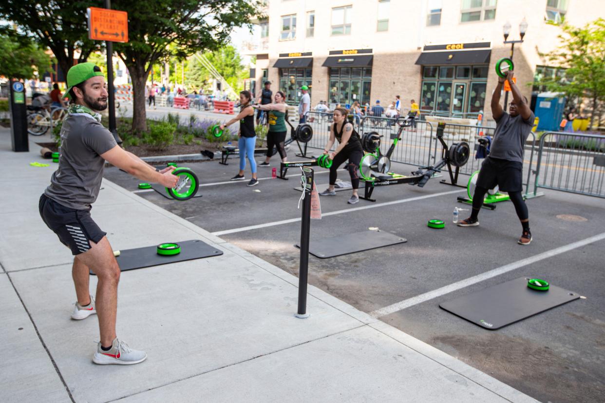 Jacob Morden leads a fitness class on a closed street in downtown Indianapolis on Friday, May 22, 2020. The city closed several streets to traffic to accommodate larger outdoor areas for restaurants to provide for social distancing and the gym was able to take advantage of the closure to teach outdoor class.