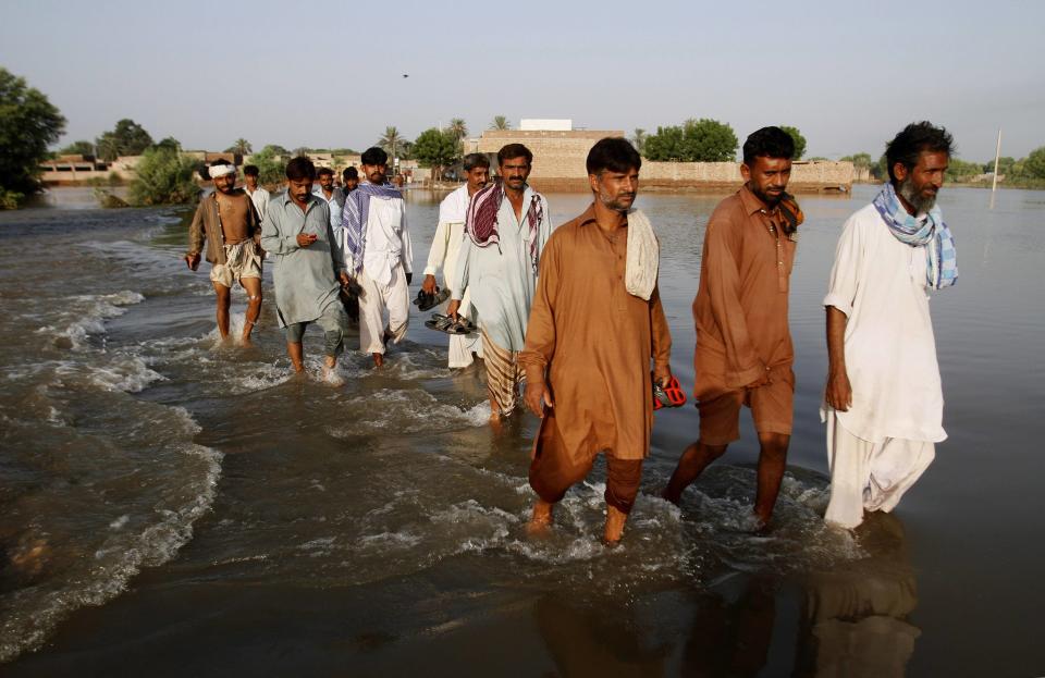 Flood victims wade through a flooded area in Muzaffargarh, Punjab province September 17, 2014. The lives of more than two million people were affected by this month's floods in Pakistan, and more than 300 were killed. REUTERS/Asim Tanveer (PAKISTAN - Tags: DISASTER ENVIRONMENT )