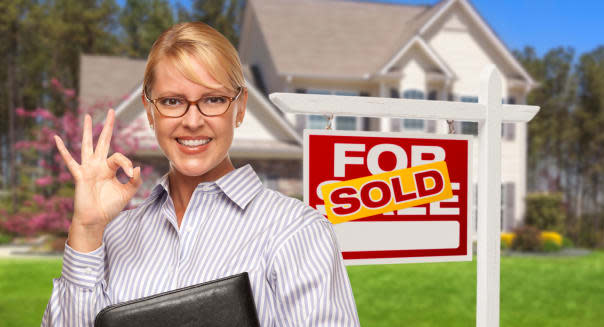 Female Real Estate Agent in Front of Sold Home For Sale Sign and House.