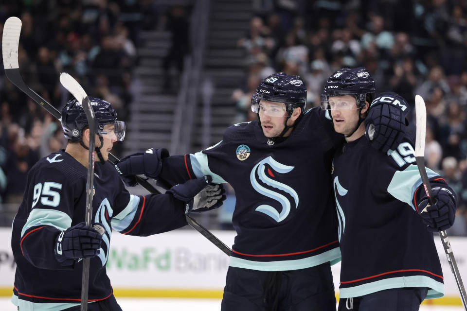 Seattle Kraken defenseman Vince Dunn, center, is congratulated by left wing Andre Burakovsky , left, and left wing Jared McCann, right. after scoring against the Vancouver Canucks during the first period of an NHL hockey game, Thursday, Feb. 22, 2024, in Seattle. (AP Photo/John Froschauer)