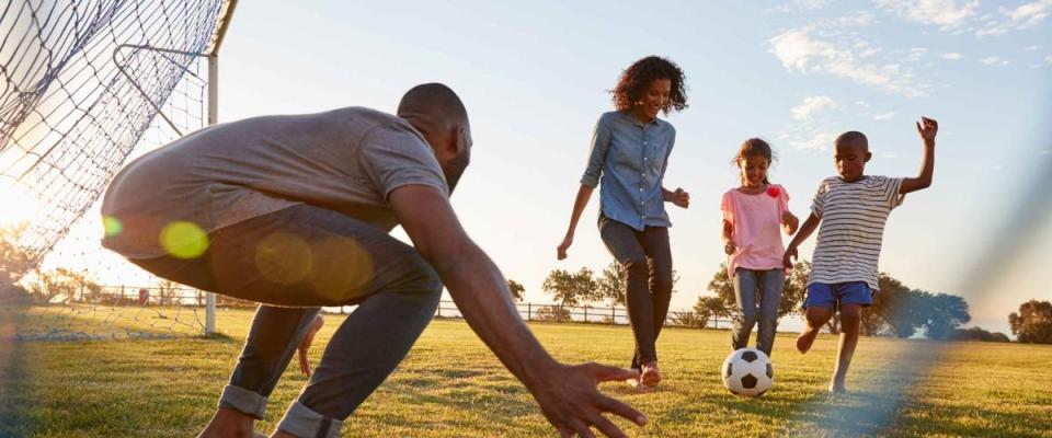 A boy kicks a football during a game with his family