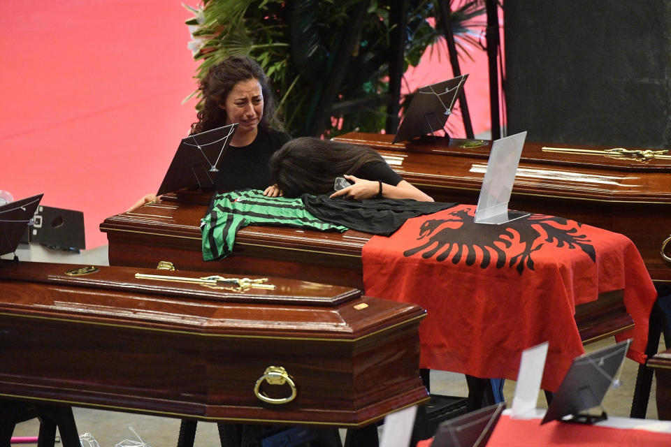 Women mourn over a coffin with the Albanian flag draped over it ahead of a state funeral, in Genoa, Italy, Saturday, Aug. 18, 2018. Saturday has been declared a national day of mourning in Italy and will include a state funeral at the industrial port city's fair grounds for those who plunged to their deaths as the 45-meter (150-foot) tall Morandi Bridge gave way Tuesday. (Luca Zennaro/ANSA via AP)