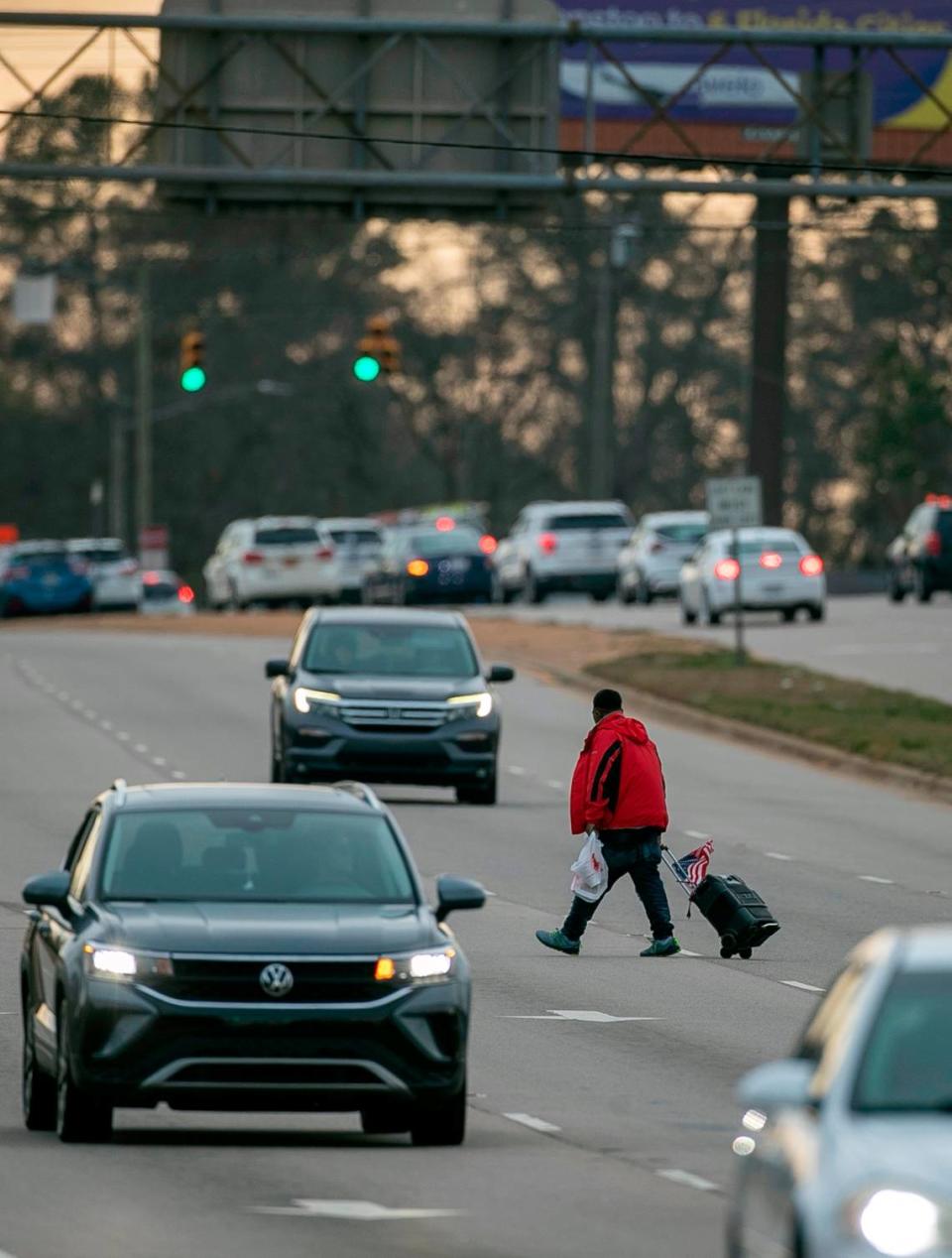 A pedestrian walks across multiple lanes of S. Wilmington Street near Chapanoke Road avoiding a marked cross walk on Wednesday, January 18, 2023 in Raleigh, N.C.