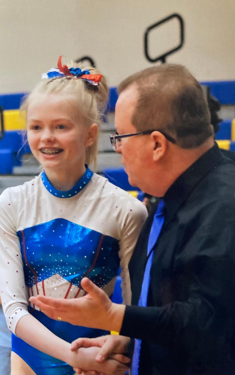 7th grader Mae Van Beek talks with Head Coach Les Coin at a gymnastics meet.