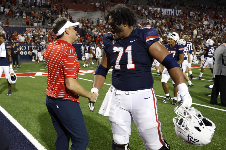 Arizona head coach Jedd Fisch shakes hands with Arizona offensive lineman Jonah Savaiinaea (71) after Arizona beat North Dakota State in an NCAA college football game Saturday, Sept. 17, 2022, in Tucson, Ariz. (AP Photo/Chris Coduto)