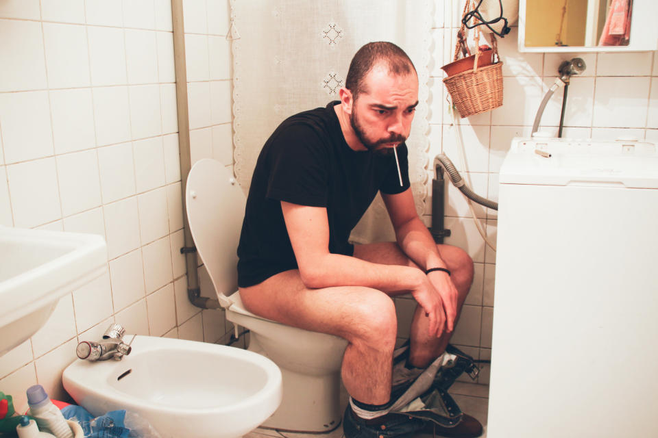 A man on the toilet next to a bidet