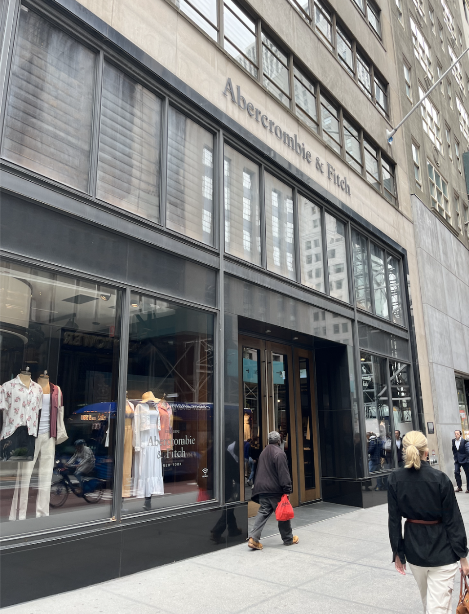 A&F storefront with some clothes hanging in the window as people walk by