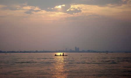 A wooden pirogue sails at dusk on the Congo River against the backdrop of high-rise buildings in the Democratic Republic of Congo's capital Kinshasa, in this March 7, 2010 file photo. REUTERS/Katrina Manson/Files