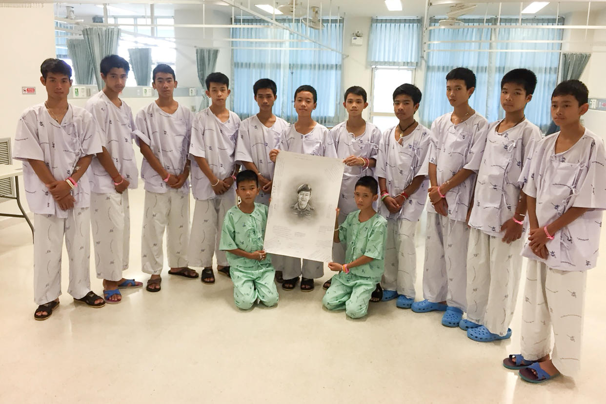 <em>The boys rescued from a flooded cave in Thailand pose with a drawing of Samarn Kunan, a former Thai navy diver who died working to rescue them (Reuters)</em>