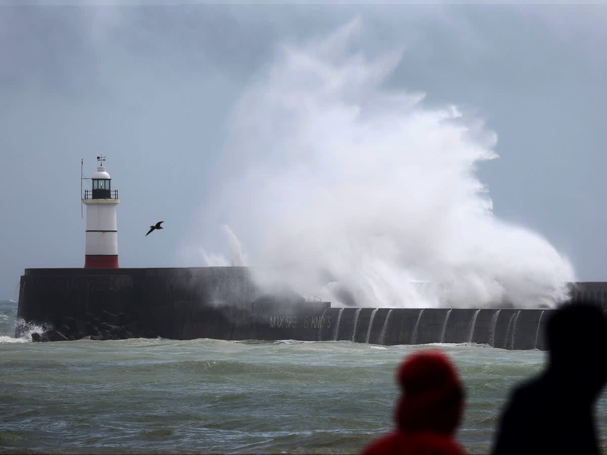 Waves crash over the breakwater by Newhaven Lighthouse, East Sussex (AFP)