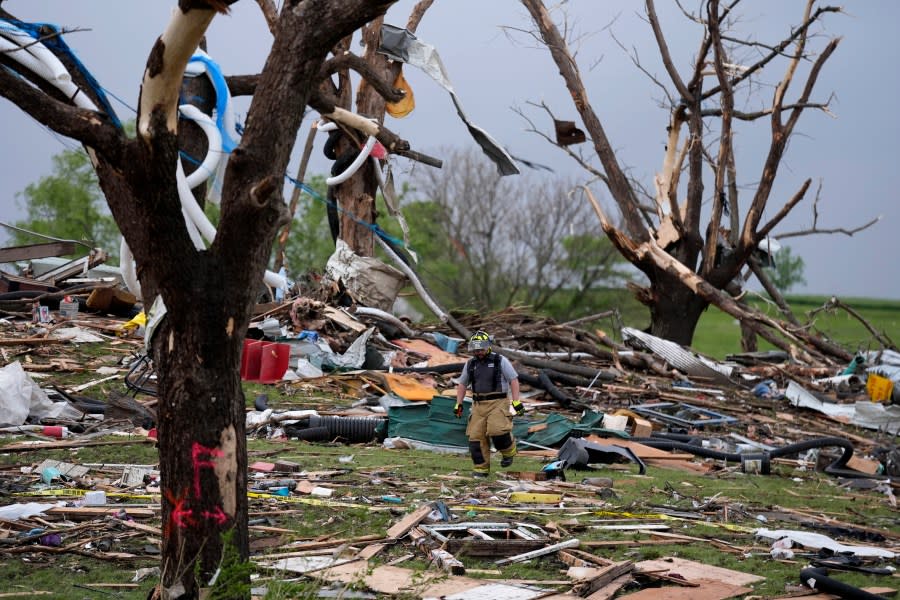 A firefighter walks among tornado-damaged homes, Tuesday, May 21, 2024, in Greenfield, Iowa. (AP Photo/Charlie Neibergall)