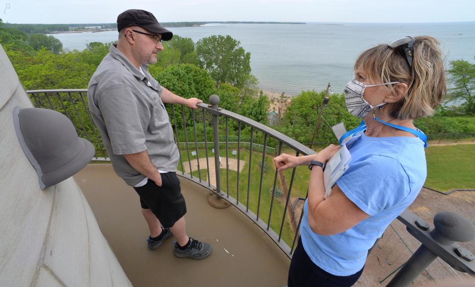 Visitor Boris Kitevski, left, of Erie, speaks with Erie Land Lighthouse volunteer docent Dell Becker on May 22, 2021. Presque Isle State Park and the entrance to Presque Isle Bay can be seen in the background center, looking north. Volunteers are needed at Erie Land Lighthouse and Presque Isle Lighthouse