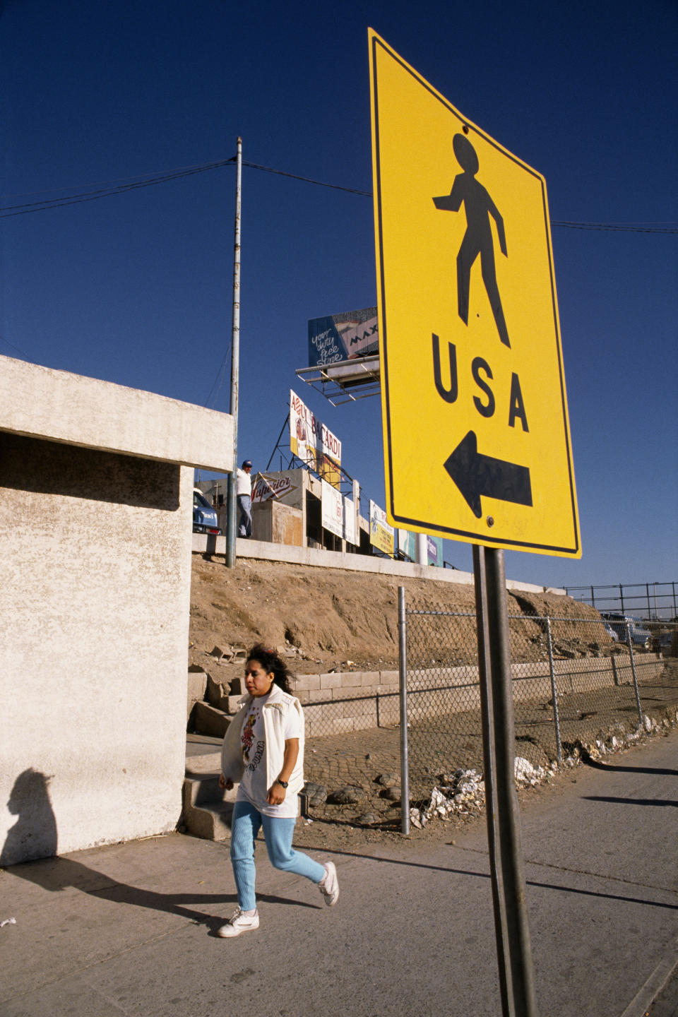 Woman walking along the America-Mexico border, near Tijuana.