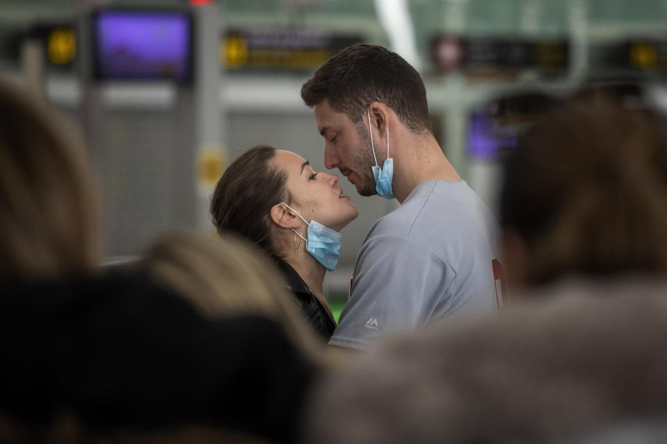 A couple kiss, at the Barcelona Airport, Spain, Thursday, March 12, 2020. Airlines and travelers are still sorting out the new travel ban that President Donald Trump announced late Wednesday, barring most foreign visitors from continental Europe for 30 days. (AP Photo/Emilio Morenatti)