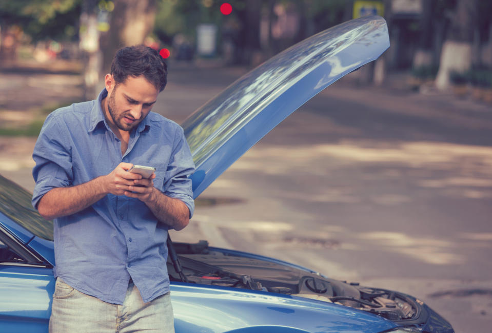 Man on phone in front of car with hood up