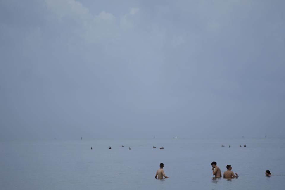 FILE - People swim in the ocean off of Crandon Park, July 28, 2023, in Key Biscayne, Fla. At about summer's halfway point, the record-breaking heat and weather extremes are both unprecedented and unsurprising, hellish yet boring in some ways, scientists say. (AP Photo/Rebecca Blackwell, File)