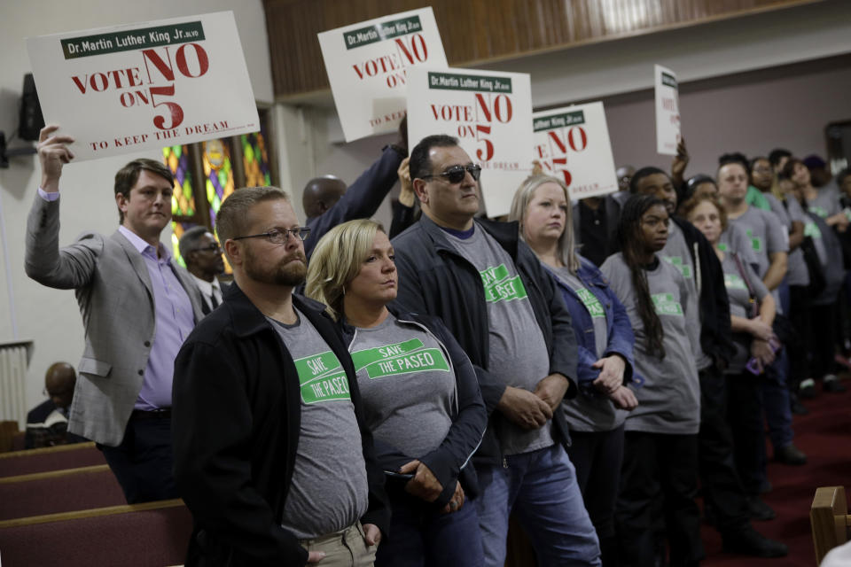 In this Sunday, Nov. 3, 2019, photo, people wearing "Save The Paseo" shirts stand among attendees at a rally to keep a street named in honor of Dr. Martin Luther King Jr. at Paseo Baptist Church in Kansas City, Mo. In January, the City Council voted to rename one of the city's main boulevards, The Paseo, after King, but many in the community want the old name back. A petition drive put the issue on the Nov. 5 ballot pitting neighbors against each other. (AP Photo/Charlie Riedel)