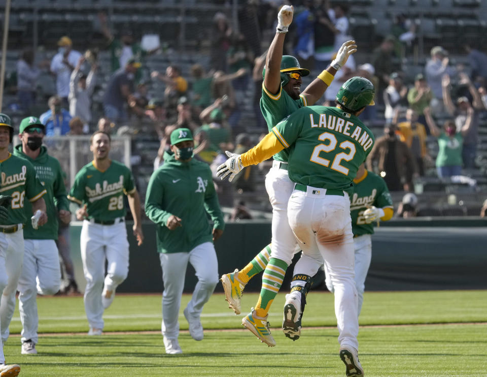 Oakland Athletics' Ramon Laureano (22) celebrates with Tony Kemp (5) and teammates after two runs scored on a throwing error by Minnesota Twins third baseman Luis Arraez during the 10th inning of a baseball game Wednesday, April 21, 2021, in Oakland, Calif. Laureano safe at first. Oakland won 13-12. (AP Photo/Tony Avelar)