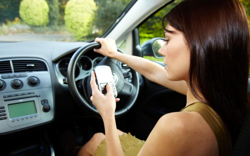 BTJNWX Woman driving and using mobile phone - Chris Rout/Alamy