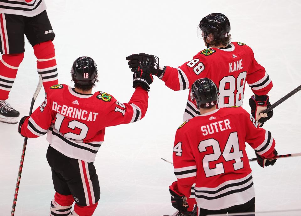 Alex DeBrincat of the Chicago Blackhawks is congratulated by Patrick Kane after scoring a second period goal against the Detroit Red Wings at the United Center in Chicago on Saturday, Feb. 27, 2021.