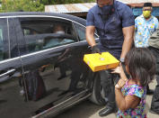 Indonesian President Joko Widodo is helped by his bodyguard to hand out a box of food to a young girl from inside his car during his visit at a quake-hit area in Mamuju, West Sulawesi, Indonesia, Tuesday, Jan. 19, 2021. Widodo visit the areas where a deadly earthquake left thousands of people homeless, to reassure them the government's response is reaching those struggling after the quake. (AP Photo/Josua Marunduh)