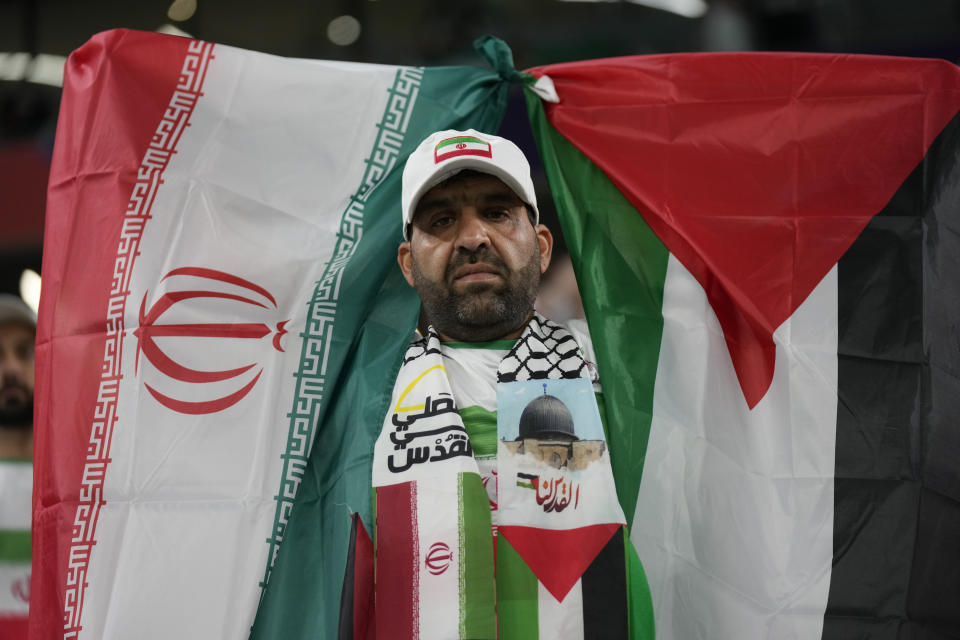 A fan holds a Palestinian, right, and an Iranian flag, ahead of the Asian Cup Group C soccer match between Iran and Palestine at the Education City Stadium in Al Rayyan, Qatar, Sunday, Jan. 14, 2024. (AP Photo/Aijaz Rahi)