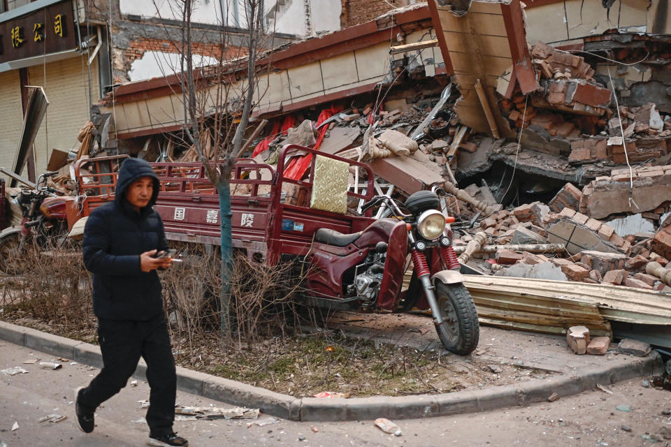 A man walks past a collapsed building after an earthquake in Dahejia, Jishishan County in northwest China's Gansu province, Dec. 19, 2023. / Credit: PEDRO PARDO/AFP/Getty