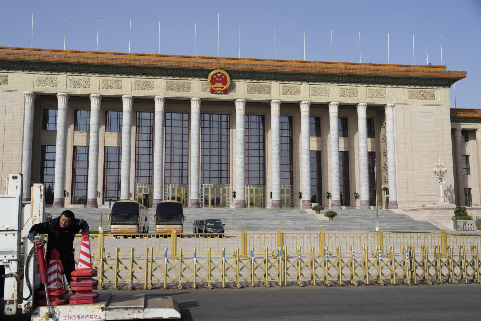 A traffic police officer deploy cones in front of the Great Hall of the People where the upcoming National People's Congress will be held in Beijing, Saturday, March 2, 2024. The first thing the legislature will do when it opens on Tuesday, March 5, 2024, is receive a lengthy "work report" from Premier Li Qiang that will review the past year and include the government's economic growth target for this year. (AP Photo/Ng Han Guan)