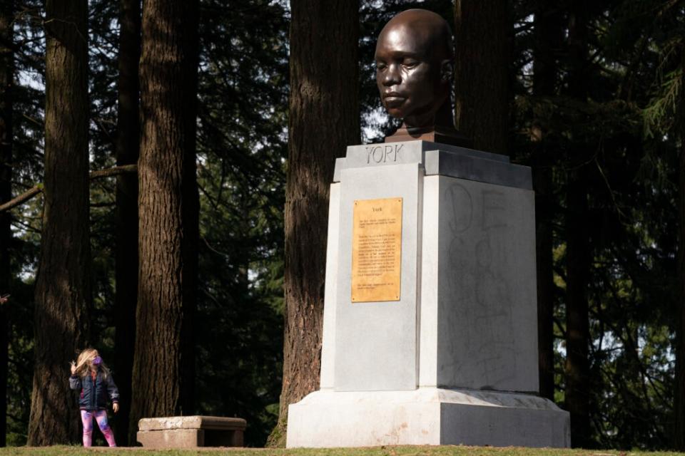 PORTLAND, OR – MARCH 01: A young visitor examines a statue of York, the only Black member of the Lewis and Clark Corps of Discovery, that was mysteriously erected in Mt. Tabor Park on March 1, 2021 in Portland, Oregon. The statue was sculpted by an unknown artist and mounted at the previous location of a memorial to Harvey Scott, a vocal conservative who fought against women’s suffrage, which was torn down by activists during racial justice protests last year. (Photo by Nathan Howard/Getty Images)