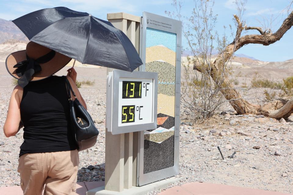 A woman stands near a digital display of an unofficial heat reading at Furnace Creek Visitor Center during a heat wave in Death Valley National Park in Death Valley, California, on July 16, 2023. California's famous Death Valley, one of the hottest places on Earth, reached 128 degrees that day.