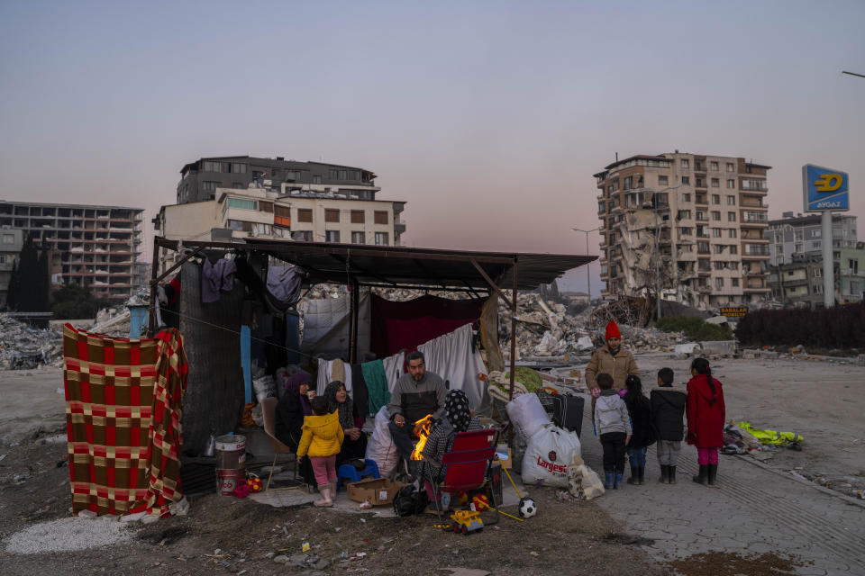 A family stays in a makeshift tent surrounded of buildings that were heavily affected during the earthquake in Antakya, southeastern Turkey, Tuesday, Feb. 14, 2023. The death toll from the earthquakes of Feb. 6, that struck Turkey and northern Syria is still climbing. (AP Photo/Bernat Armangue)