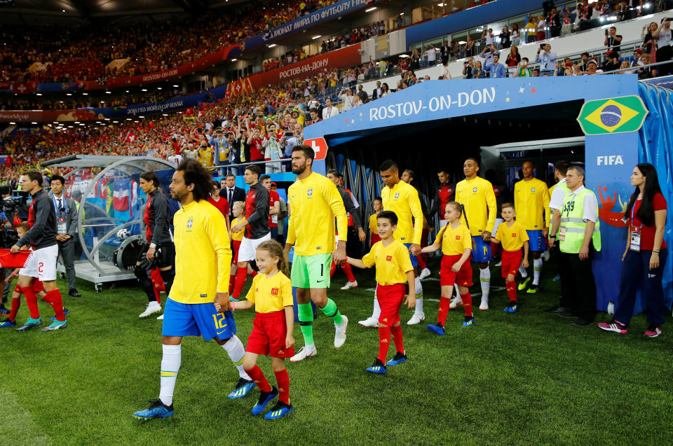 <p>The Brazil and Switzerland players walk out on to the pitch with mascots before the match </p>