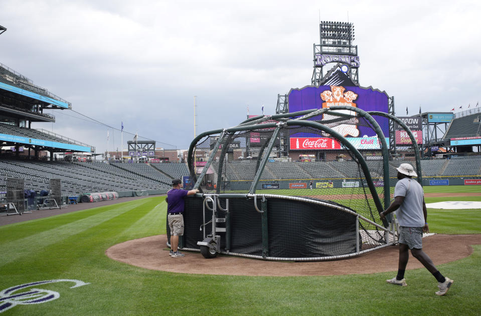 Grounds crew members pull down the batting cage after the postponement of a baseball game between the Colorado Rockies and the San Francisco Giants on Thursday, Sept. 14, 2023, in Denver. The game was rescheduled as part of a doubleheader Saturday. (AP Photo/David Zalubowski)