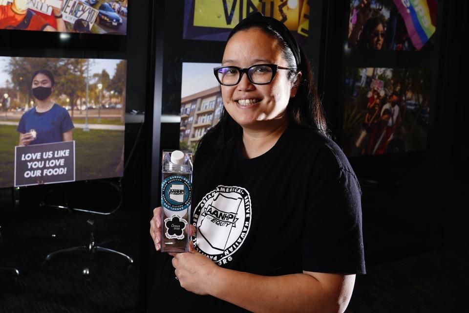 Jennifer Chau, director of the Arizona Asian American Native Hawaiian and Pacific Islander For Equity Coalition, holds a boba drink carton at her office Friday, April 8, 2022, in Tempe, Ariz. (AP Photo/Ross D. Franklin)