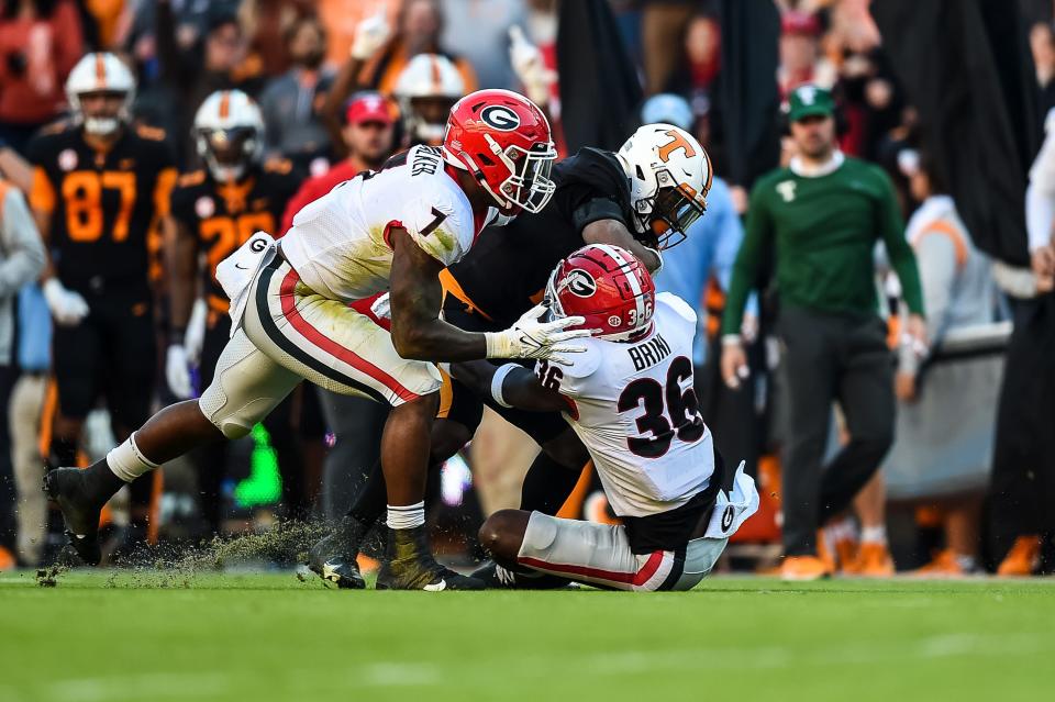 Georgia defensive back Latavious Brini (36) and linebacker Quay Walker (7) tackle Tennessee quarterback Hendon Hooker during the first quarter of their 2021 game at Neyland Stadium.
