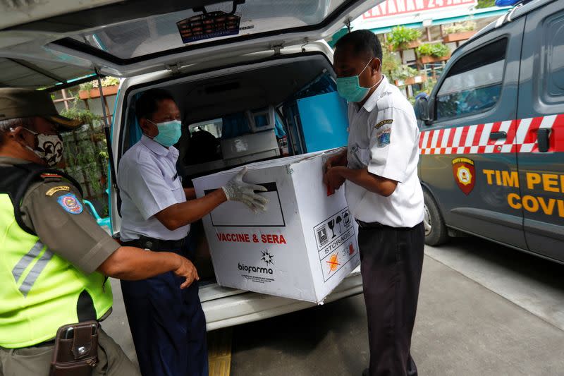 Officers carry off a box of the coronavirus disease (COVID-19) vaccine, in Jakarta