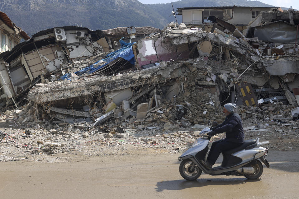 A man rides a motorbike past destroyed buildings in Antakya, southeastern Turkey, Tuesday, Feb. 21, 2023. The death toll in Turkey and Syria rose to eight in a new and powerful earthquake that struck two weeks after a devastating temblor killed nearly 45,000 people, authorities and media said Tuesday. (AP Photo/Unal Cam)