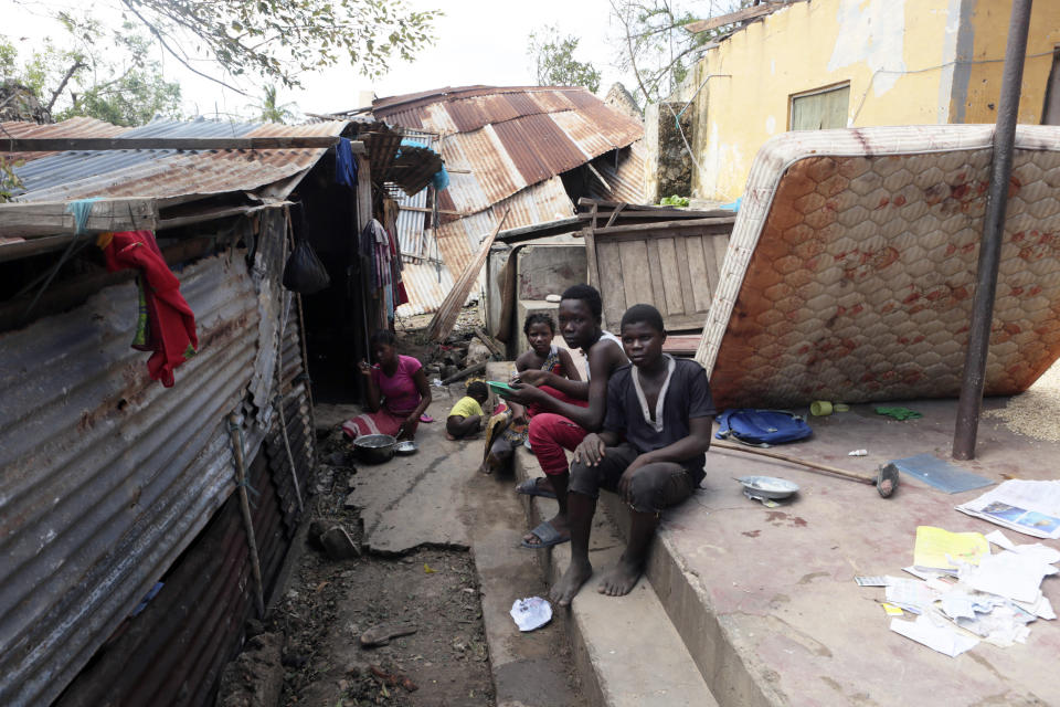 A family is seen outside their house which got damaged by Cyclone Kenneth in Ibo island north of Pemba city in Mozambique, Wednesday, May, 1, 2019. The government has said more than 40 people have died after the cyclone made landfall on Thursday, and the humanitarian situation in Pemba and other areas is dire. More than 22 inches (55 centimeters) of rain have fallen in Pemba since Kenneth arrived just six weeks after Cyclone Idai tore into central Mozambique. (AP Photo/Tsvangirayi Mukwazhi)