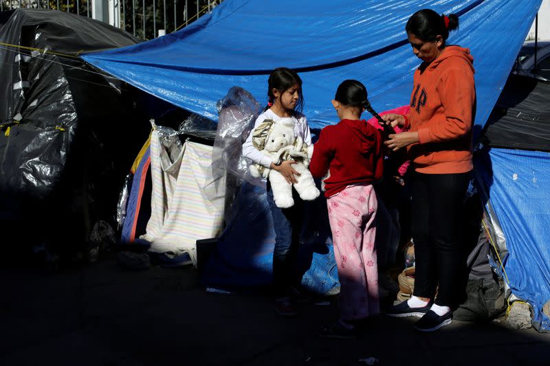 Mexican asylum seekers, who are camping near the Paso del Norte international border crossing bridge while waiting to apply for asylum to the U.S., gather outside their tents in Ciudad Juarez