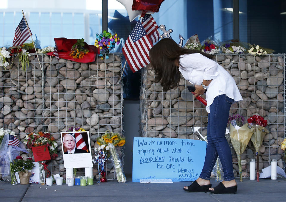Thu-Van Cunningham, of Phoenix, reads messages left by well-wishers as she visits a makeshift memorial in honor of the late Arizona Republican Sen. John McCain at McCain's office Monday, Aug. 27, 2018, in Phoenix. McCain, the war hero who became the GOP's standard-bearer in the 2008 election, died at the age of 81, Saturday, Aug. 25, 2018, after battling brain cancer. (AP Photo/Ross D. Franklin)