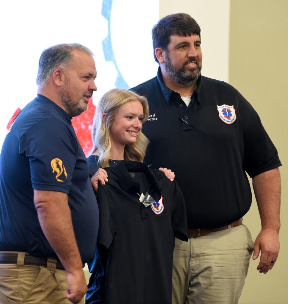 Hale County EMS employees Russell Weeden and Patrick Howard pose with Aleice Stevens as she shows off her Hale County EMS shirt at Tuscaloosa Career and Technology Academy as local industries sign high school students to internships and jobs Wednesday, May 10, 2023, sponsored by West Alabama Works.